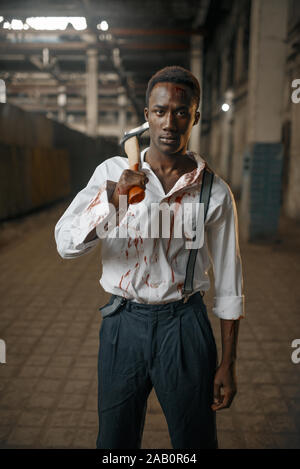 Uomo con ax in fabbrica abbandonata, terra di zombie Foto Stock