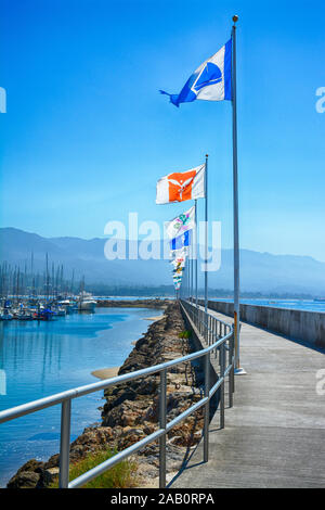 Un ampia veduta della scogliera lungomare accanto a una sfilata di bandiere internazionali sul Santa Barbara Porto di Santa Barbara, CA, Stati Uniti d'America Foto Stock