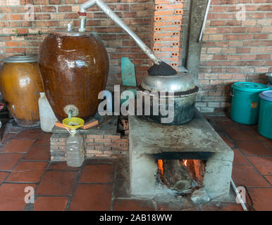 In Cai Be, Mekong Deltal, Vietnam - Marzo 13, 2019: installazione distilles fermentato di riso e miele da liquido di riscaldamento per vaporizzare alcol e non il wat Foto Stock