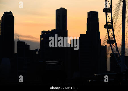 (Fuoco selettivo) vista incredibile della silhouette della skyline di Singapore con una ruota panoramica Ferris durante un tramonto mozzafiato. Foto Stock