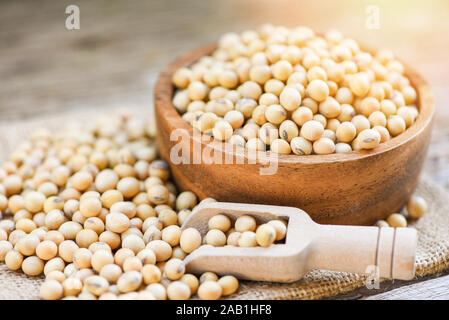 Semi di soia in una ciotola di legno prodotti agricoli sul sacco background / secco Fave di soia Foto Stock
