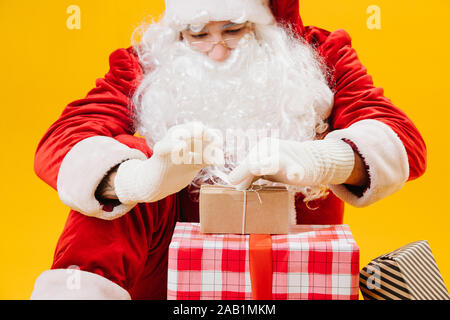 Babbo Natale seduto sul pavimento, attentamente la legatura poco presenti davanti a lui Foto Stock