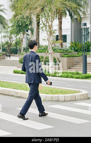 Imprenditore della tuta con carta pacchetto con pranzo e strada di attraversamento Foto Stock