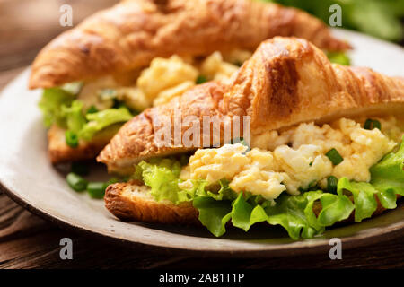 Croissant sandwich con uovo e formaggio insalata verde foglia di insalata. Una gustosa colazione sana Foto Stock