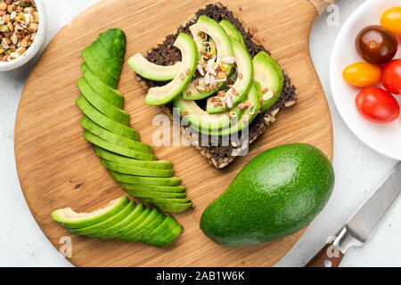 Fette di Avocado con bean di germogli di semi sul pane di segale tostato. Tabella vista dall'alto. Vegano sano cibo vegetariano Foto Stock