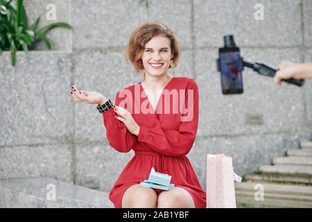 Ridere bella giovane donna divertirsi durante le riprese video di circa alla moda di pezzi di gioielleria Foto Stock