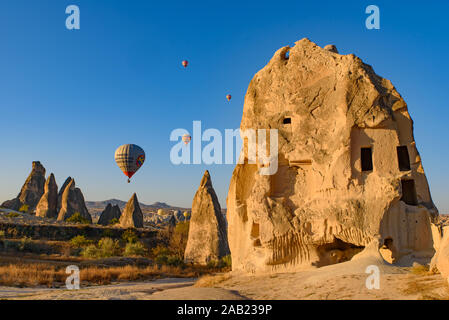 Volare i palloni ad aria calda e il paesaggio di roccia all'orario di alba a Goreme, Cappadocia, Turchia Foto Stock