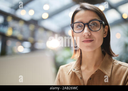 Ritratto di imprenditrice contemporaneo con gli occhiali sorridente alla videocamera mentre si lavora in outdoor cafe, spazio di copia Foto Stock