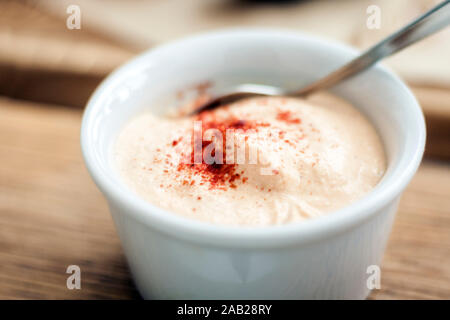 Yogurt bianco salsa con la paprica in una piccola ciotola per meze tradizionale cena sul tavolo di legno nel ristorante Foto Stock