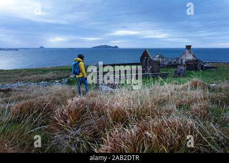 Donna in piedi su una collina in erba alta dalla rovina di Kirrary School house presenti nel film "Ryan della figlia' a Dunquin, Kerry, Irlanda Foto Stock