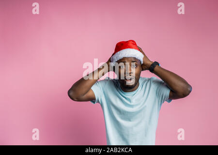 Storditi bello barba lunga dark scuoiati maschio, essendo sconvolti dai prezzi sulla vendita di natale, mantenendo le mani sul capo, isolate su sfondo rosa. Emozioni Foto Stock
