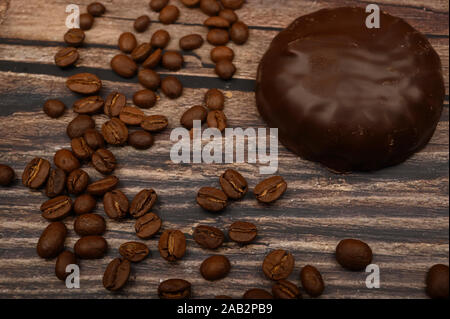 Marshmallow in cioccolato e chicchi di caffè su sfondo di legno. Close up Foto Stock