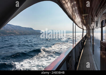 Bella vista sul mare Adriatico con le isole e il sole sparato dal ponte a bordo di una barca con dettagli in legno. Le onde in acqua, vista Foto Stock