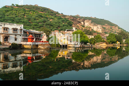 Bundi, Rajasthan, India. Nawal Sagar lago e Palazzo di città sulla collina con edifici lungo il lago e alberi con riflessioni, Bundi, Rajasthan, Foto Stock