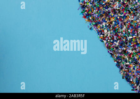 Frantumato circolare palline di plastica parti realizzate multicolore di plastica riciclata raccolte in mare flatlay su uno sfondo blu per essere usato per un prodotto nuovo Foto Stock