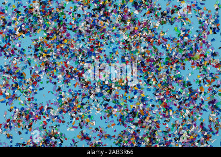 Frantumato circolare palline di plastica, parti realizzate multicolore di plastica riciclata raccolte in mare flatlay spalmato su uno sfondo blu per essere usato per nuovo Foto Stock