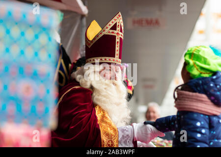 Eindhoven, Paesi Bassi, 23 novembre 2019. Sinterklaas indossa il suo costume rosso e mitra agitando la mano di un bambino. Festival olandese evento per chil Foto Stock