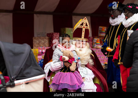 Eindhoven, Paesi Bassi, 23 novembre 2019. Sinterklaas indossa il suo costume e avente una piccola ragazza il suo laboratorio in posa per la telecamera e dando Foto Stock