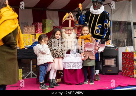 Eindhoven, Paesi Bassi, 23 novembre 2019. Sinterklaas indossa il suo costume e avente bambine accanto a lui mentre posa per la telecamera e g Foto Stock