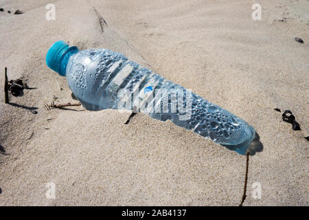 Eine angespülte Mineralwasserflasche aus Kunststoff auf einer Sandbank im watt |alluvionale una bottiglia di acqua minerale di plastica su un banco di sabbia in borra Foto Stock