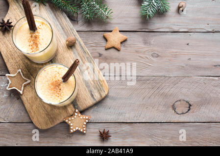 Zabaione drink di Natale con una grattugiata di noce moscata e cannella bastoni per le vacanze di Natale ed invernali, su sfondo di legno, vista dall'alto, copia dello spazio. Foto Stock