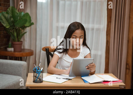 Asian teenager fare i compiti a casa utilizzando tablet Foto Stock