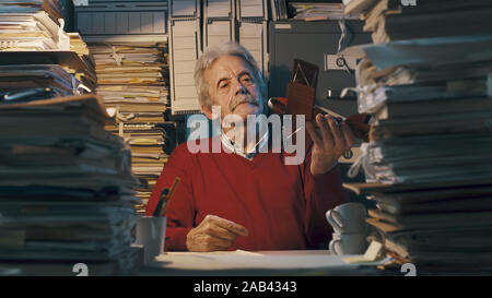 Senior pigro lavoratore di ufficio con vintage toy piano: egli è giocare e divertirsi invece di lavorare Foto Stock