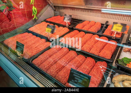 Materie carni macinate in un negozio di macellaio, refrigerate di prodotti a base di carne sul contatore. Foto Stock