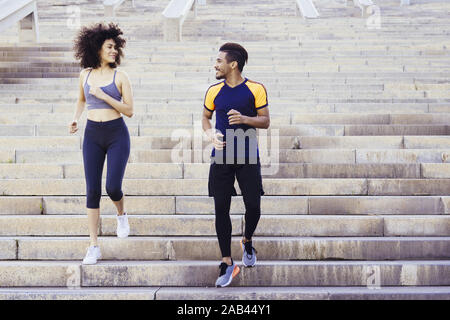 Felice giovane coppia guide in esecuzione al piano di sotto sulla città di scale, fitness, urban allenamento sportivo e di uno stile di vita sano concetto, copia spazio per il testo Foto Stock