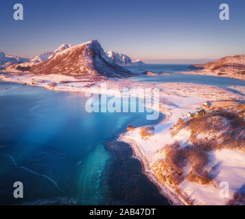 Vista aerea di montagne coperte di neve, case, acqua chiara Foto Stock