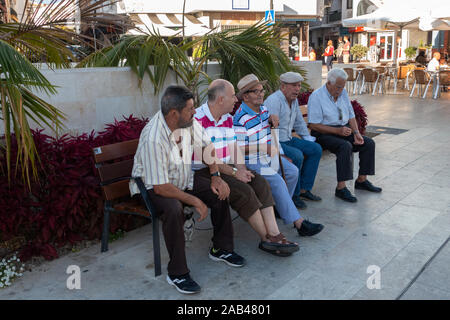 Vecchi uomini seduti su una panchina di strada godendo la loro giornata a Estepona, Spagna Foto Stock