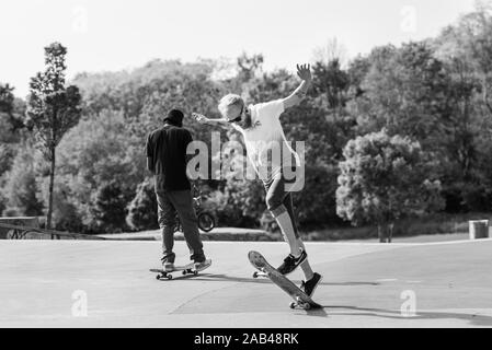 Skateboarders facendo trucchi, praticando ollieing presso i locali di città skatepark in Stoke on Trent, Stoke Plaza Foto Stock