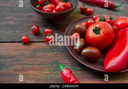 Piccoli freschi pomodori e peperone piccante nella piastra da cucina