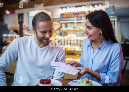 Moglie sorridere mentre mostra il suo futuro marito matrimonio inviti Foto Stock