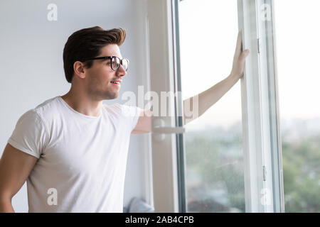 La mano dell'uomo apre la finestra . Ventilare una casa in tempo caldo. Foto Stock