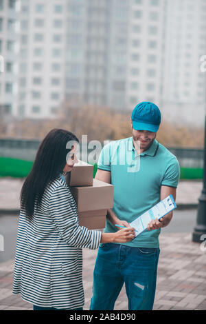 Donna dichiarazione di firma dopo aver ricevuto il suo pacchi Foto Stock