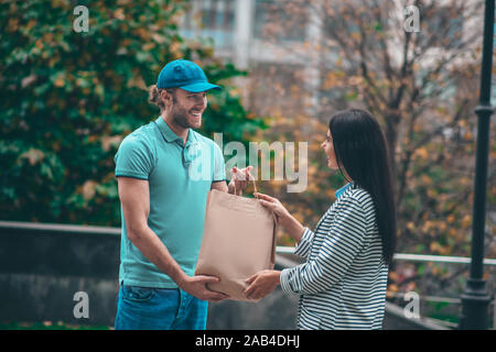 Donna sorridente mentre sta assumendo il sacchetto da uomo di consegna Foto Stock