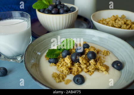 Fotografia di cibo di colazione consistente di yogurt, muesli e cereali mirtilli su uno sfondo blu Foto Stock