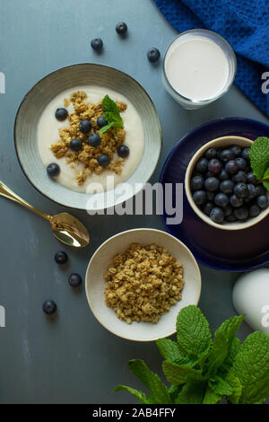 Fotografia di cibo di colazione consistente di yogurt, muesli e cereali mirtilli su uno sfondo blu Foto Stock