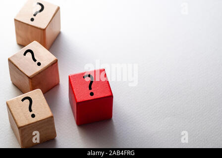 Individualità, la diversità e il concetto di leadership con tre naturale cubi di legno e un cubo rosso stampato con un punto interrogativo su uno sfondo bianco con Foto Stock