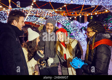Happy amici divertendosi nel night Christmas party all'aperto. Foto Stock