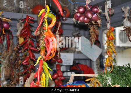 Caldo fresco peperoni colorati sul piedistallo con altri tipi di frutta e verdura sul mercato pubblico Foto Stock