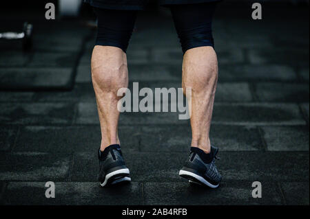 Gambe addestrati con vitelli muscolare in sneakers nella palestra di formazione Foto Stock