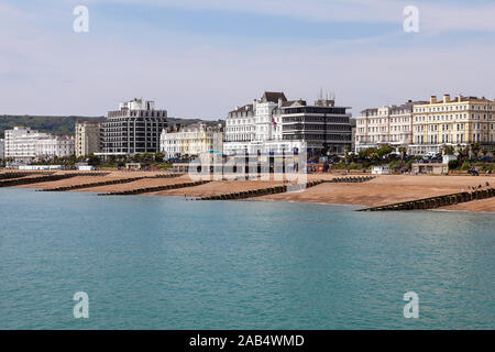 Hotel sul lungomare e pennelli multipli sulla spiaggia di Eastbourne, visto qui su un nuvoloso giorno nel maggio 2019. Foto Stock