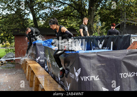 Sebbene Viking ostacolo corso i partecipanti gara salta fuori di acqua ghiacciata in piscina a Helsinki, Finlandia Foto Stock