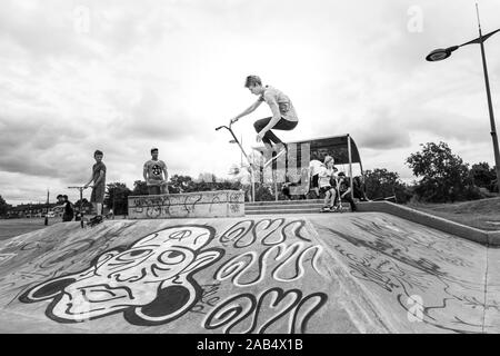 Uno dei migliori del Regno Unito scooteristi Josh praticanti di vetro presso il locale skatepark, fare acrobazie in tutto il skatepark con persone che guardano sul Foto Stock