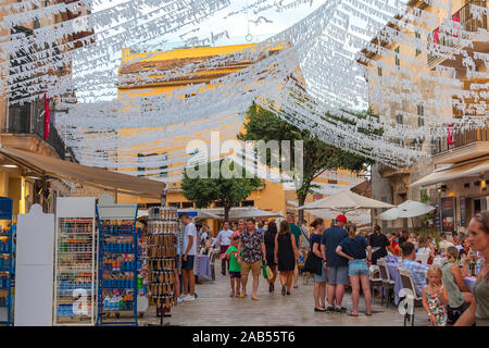 ALCUDIA, Spagna - Luglio 8, 2019: Ristorante tavoli su strada con i turisti in mare Alcudia città vecchia, isola di Mallorca, Spagna Foto Stock