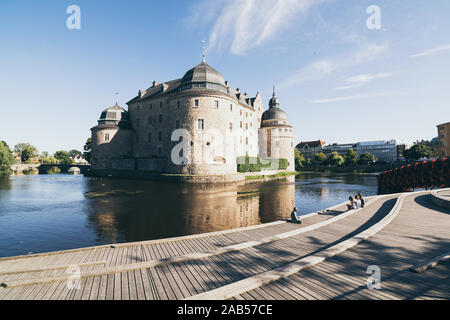 Orebro, Svezia - Agosto 2017: persone rilassarsi di fronte all antica Orebro castle al tramonto Foto Stock