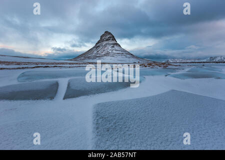 Famosa montagna con cascate in Islanda, kirkjufell, inverno in Islanda, ghiaccio e neve, riflessioni, giallo Erba, natura, ic Foto Stock