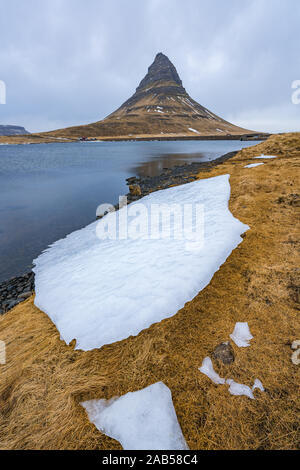 Famosa montagna con cascate in Islanda, kirkjufell, inverno in Islanda, ghiaccio e neve, riflessioni, giallo Erba, natura, ic Foto Stock